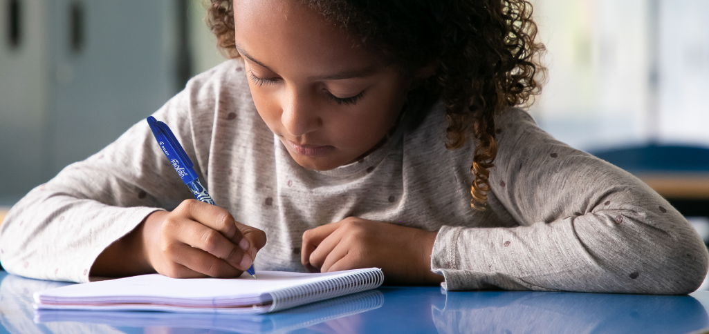 une enfant qui écrit dans un cahier